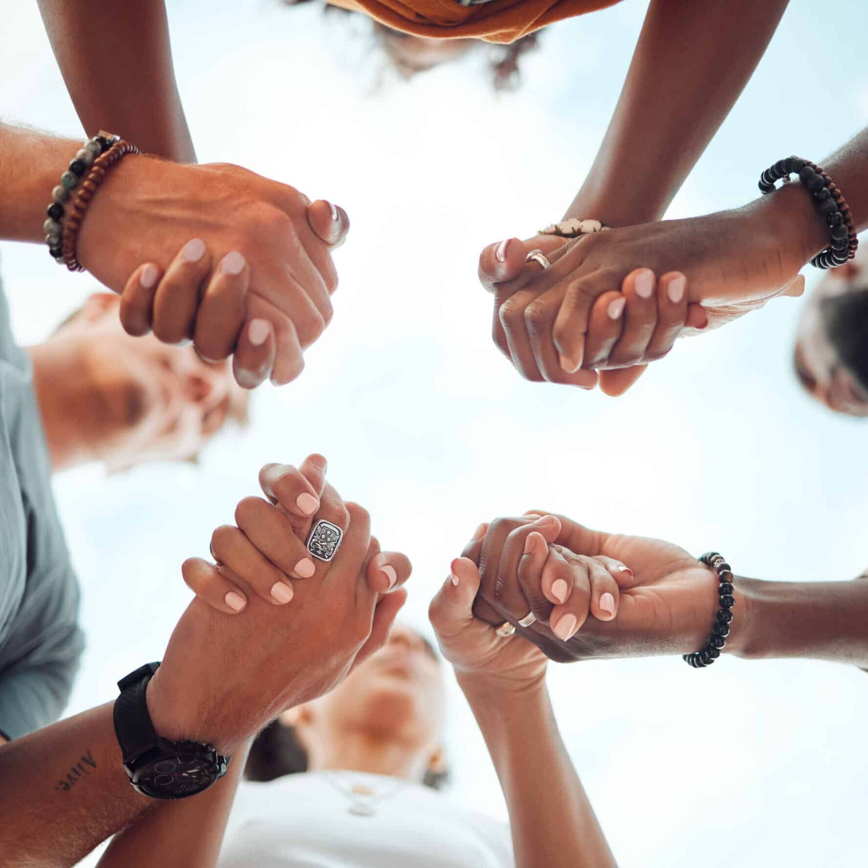 Holding hands, support and friends praying for spiritual growth, community and gratitude together with sky from below. Group of people in partnership for hope, love and human faith in connection.
